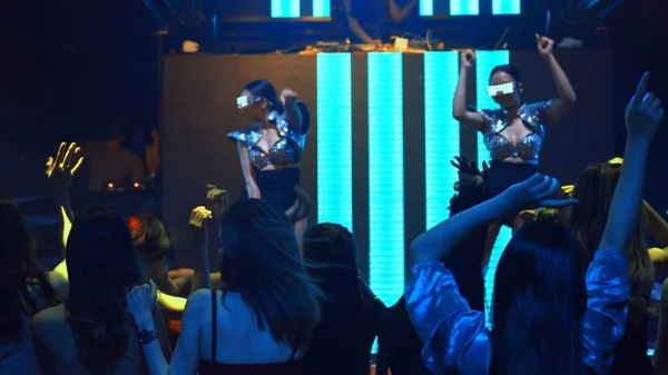 Группа людей танцует в дискотечном ночном клубе под ритм музыки от DJ на сцене — стоковое фото