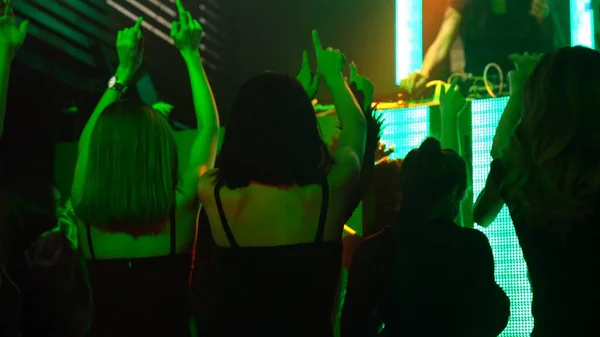 Group of people dance in disco night club to the beat of music from DJ on stage — Stock Photo, Image