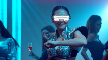 Bir grup insan disko gece kulübünde DJ 'in sahnede çaldığı müzikle dans ediyor.