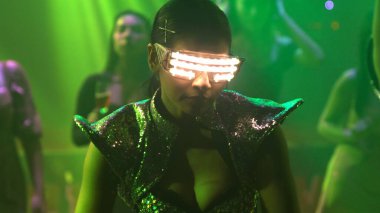 Bir grup insan disko gece kulübünde DJ 'in sahnede çaldığı müzikle dans ediyor.