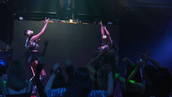 Grupo de personas bailan en discoteca al ritmo de la música de DJ en el escenario — Foto de Stock