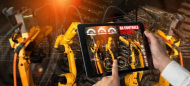 Mühendis, artırılmış gerçeklik endüstrisi teknolojisiyle robotik kolları kontrol ediyor.