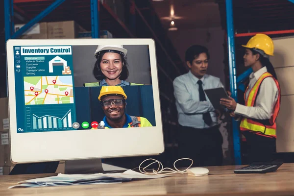 Warehouse staff talking on video call at computer screen in storage warehouse