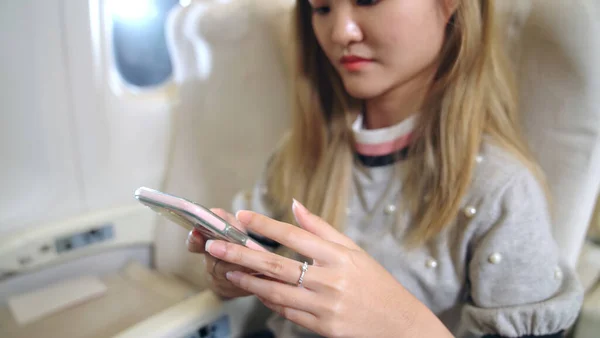 Азиатка с помощью мобильного телефона в самолете — стоковое фото