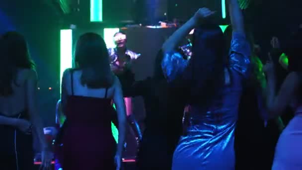 Grupo de personas bailan en discoteca al ritmo de la música de DJ en el escenario — Vídeo de stock
