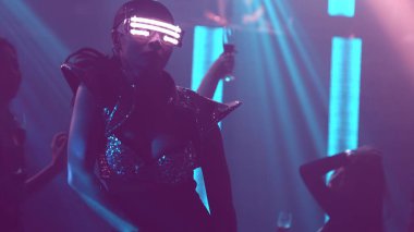 Bir grup insan disko gece kulübünde DJ 'in sahnede çaldığı müzikle dans ediyor.