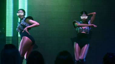 Bir grup insan disko gece kulübünde DJ 'in sahnede çaldığı müzikle dans ediyor.