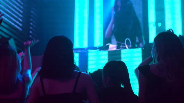 Kelompok orang menari di klub malam disko dengan irama musik dari DJ di atas panggung — Stok Foto