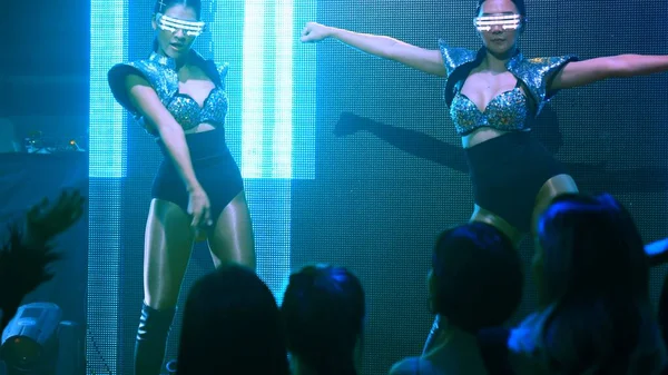 Bir grup insan disko gece kulübünde DJ 'in sahnede çaldığı müzikle dans ediyor.