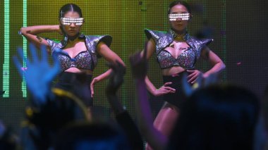 Bir grup insan disko gece kulübünde DJ 'in sahnede çaldığı müzikle dans ediyor.