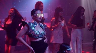 Bir grup insan disko gece kulübünde DJ 'in sahnede çaldığı müzikle dans ediyor.