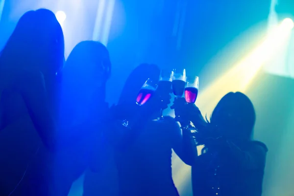 Silhouette image of people dance in disco night club to music from DJ on stage