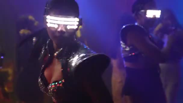 Groep mensen dansen in disco nachtclub op de beat van muziek van DJ op het podium — Stockvideo