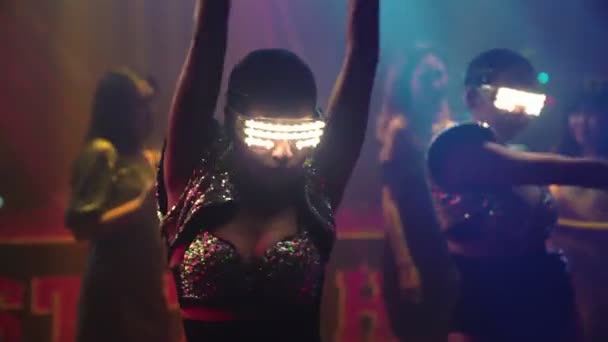 Gruppe av mennesker danser i diskonattklubb etter rytmen fra DJ-en på scenen – stockvideo