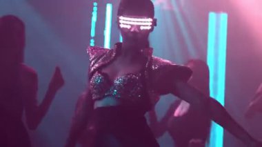 Bir grup insan disko gece kulübünde DJ 'in sahnede çaldığı müzikle dans ediyor.