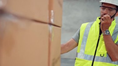 Profesyonel kargo işçisi başka bir işçiyle bağlantı kurmak için telsizle konuşuyor.