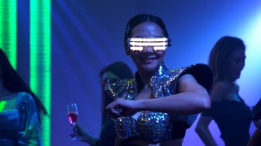 Bir grup insan disko gece kulübünde DJ 'in sahnede çaldığı müzikle dans ediyor.