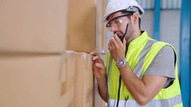 Profesyonel kargo işçisi başka bir işçiyle bağlantı kurmak için telsizle konuşuyor.