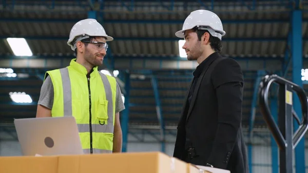 Two factory workers working and discussing manufacturing plan in the factory .