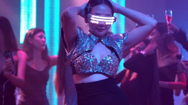 Bir grup insan disko gece kulübünde DJ 'in sahnede çaldığı müzikle dans ediyor.