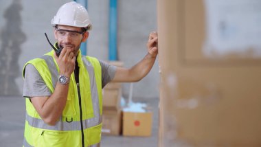 Profesyonel kargo işçisi başka bir işçiyle bağlantı kurmak için telsizle konuşuyor.