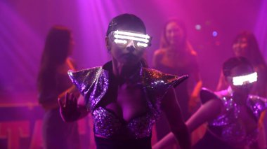 Bir grup insan disko gece kulübünde DJ 'in sahnede çaldığı müzikle dans ediyor.
