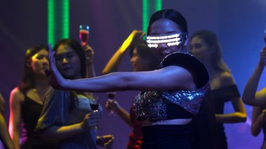 Bir grup insan disko gece kulübünde DJ 'in sahnede çaldığı müzikle dans ediyor.