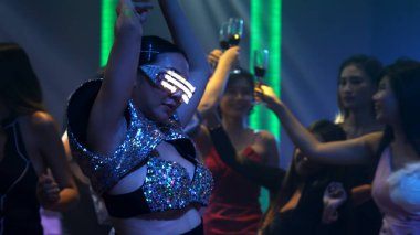 Bir grup insan disko gece kulübünde DJ 'in sahnede çaldığı müzikle dans ediyor.
