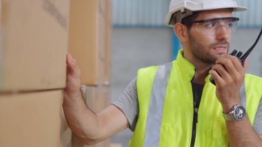 Profesyonel kargo işçisi başka bir işçiyle bağlantı kurmak için telsizle konuşuyor.
