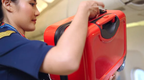 Cabin crew lift luggage bag in airplane