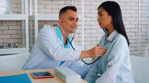 Doutor em uniforme profissional examinando paciente no hospital — Fotografia de Stock