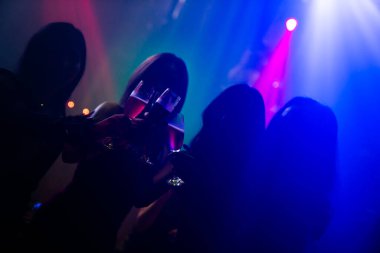 Disko gece kulübünde DJ 'in sahnede yaptığı müzikle dans eden insanların silueti.