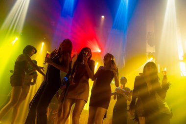 Disko gece kulübünde DJ 'in sahnede yaptığı müzikle dans eden insanların silueti.