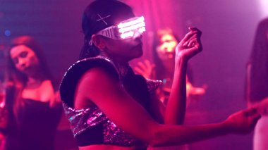 Bir grup insan disko gece kulübünde DJ 'in sahnede çaldığı müzikle dans ediyor.