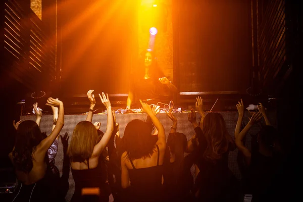 Group of people dance in disco night club to the beat of music from DJ on stage — Stock Photo, Image