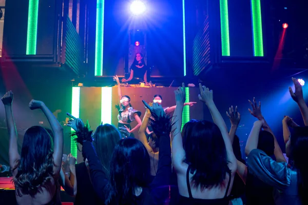 Grupo de pessoas dançam em discoteca à batida de música de DJ no palco — Fotografia de Stock