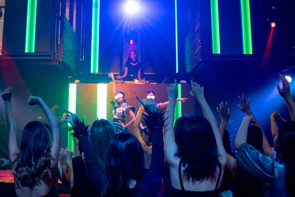 Grupo de personas bailan en discoteca al ritmo de la música de DJ en el escenario —  Fotos de Stock