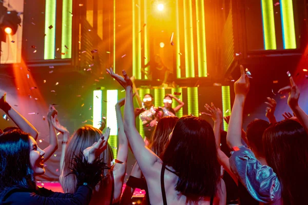 Grupo de personas bailan en discoteca al ritmo de la música de DJ en el escenario — Foto de Stock