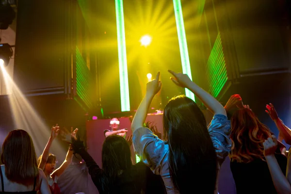Group of people dance in disco night club to the beat of music from DJ on stage — Stock Photo, Image