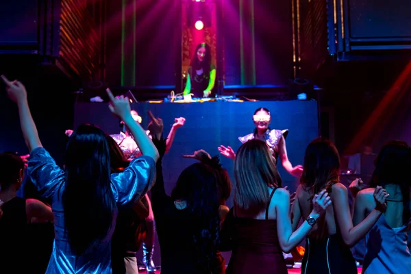 Grupo de personas bailan en discoteca al ritmo de la música de DJ en el escenario — Foto de Stock