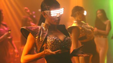 Bir grup insan disko gece kulübünde DJ 'in sahnede çaldığı müzikle dans ediyor.