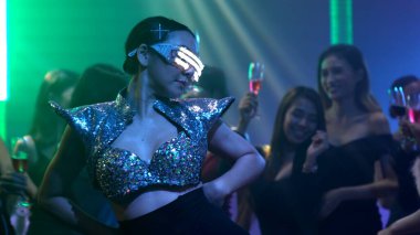 Bir grup insan disko gece kulübünde DJ 'in sahnede çaldığı müzikle dans ediyor.