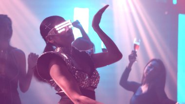 Bir grup insan disko gece kulübünde DJ 'in sahnede çaldığı müzikle dans ediyor.
