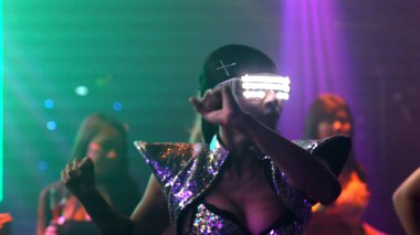 Bir grup insan disko gece kulübünde DJ 'in sahnede çaldığı müzikle dans ediyor.