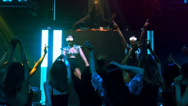 Groupe de personnes dansent en discothèque au rythme de la musique de DJ sur scène — Photo