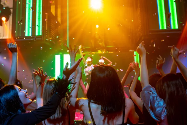 Group of people dance in disco night club to the beat of music from DJ on stage — Stock Photo, Image