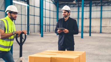 Fabrika işçileri depodaki bir yük arabasında kutu teslimatı yapıyor. .