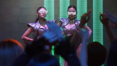 Bir grup insan disko gece kulübünde DJ 'in sahnede çaldığı müzikle dans ediyor.