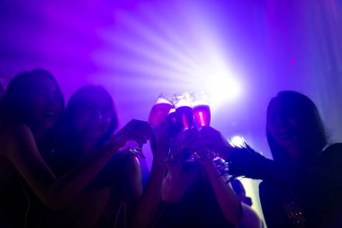 Disko gece kulübünde DJ 'in sahnede yaptığı müzikle dans eden insanların silueti.