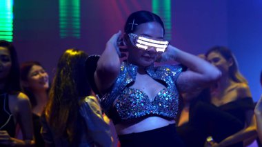 Bir grup insan disko gece kulübünde DJ 'in sahnede çaldığı müzikle dans ediyor.